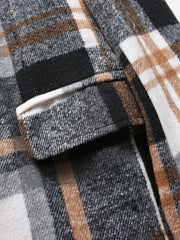 A close-up view of a brown, black, and white plaid blazer featuring a flap pocket.