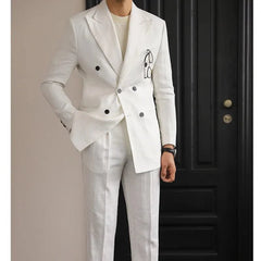 A man wears a white double-breasted linen suit with a slim fit and peak lapels.