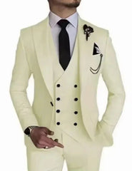 A man wears a cream-colored three-piece suit with a black tie and a decorative lapel pin.