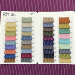 A fabric swatch book displaying various colors of pinstriped textile samples for custom suits.