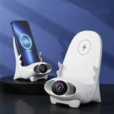 Two white chair-shaped wireless charging stands, one holding a smartphone, on a dark surface.