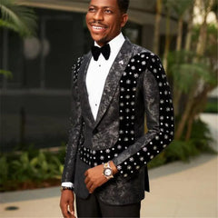 A man wears a slim-fit black floral tuxedo jacket with velvet panels and crystal embellishments.