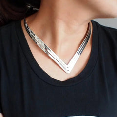 A woman wears a three-layer V-shaped silver metal torque choker necklace.