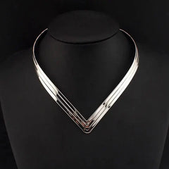 A three-layer V-shaped silver metal torque choker necklace on a black display stand.