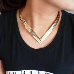 A woman wears a three-layer gold-tone metal V-shaped torque choker necklace.