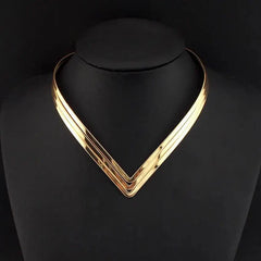 A three-layer gold-tone metal torque choker necklace with a geometric V-shaped design.