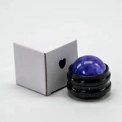 A blue resin massage roller ball sits in a black circular base next to a small white box.
