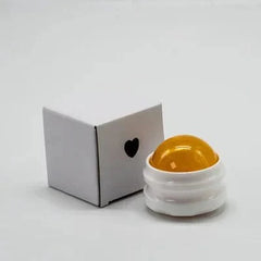 An orange manual massage roller ball sits next to its small white box with a heart cutout.