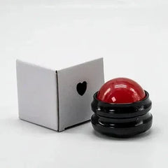 A red resin massage ball with a black handle sits next to its small white box.