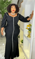 A woman wears a black long-sleeved maxi dress with a central white zipper and ruched detailing.