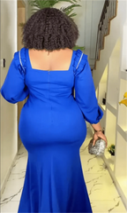 A woman wears a royal blue, long-sleeved, floor-length mermaid dress with a square neckline.