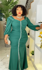 A woman wears a long-sleeved, emerald green maxi dress with a ruched bodice and white trim.
