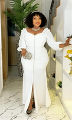 A woman wears a white, long-sleeved, floor-length maxi dress with a front slit and button detail.