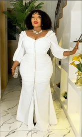 A woman wears a white, long-sleeved, floor-length maxi dress with a front slit and ruched bodice.