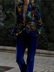 A person wears a slim-fit suit featuring a vibrant blue and gold circular print jacket and pants.