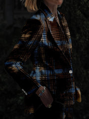 A person wears a slim-fit blazer featuring a dark blue and brown digital plaid print.