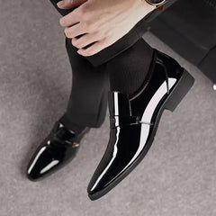 A pair of black glossy artificial leather penny loafers for men with a slip-on design.
