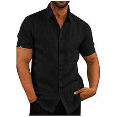A man wears a black short-sleeved button-down shirt with a chest pocket.