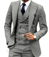 A man wears a slim-fit grey three-piece suit featuring a double-breasted vest and a black tie.