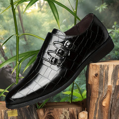 A black, pointed-toe men's dress shoe with a crocodile-embossed finish and three side buckles.