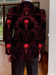 A man wears a black blazer featuring an all-over red skull and ornate damask pattern.