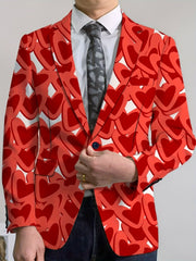 A man wears a red blazer featuring an all-over heart pattern with a white shirt and grey tie.