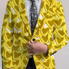 A man wears a yellow blazer featuring a repeating heart pattern over a white shirt and dark tie.