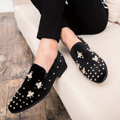 Black corduroy slip-on dress shoes featuring gold bee embellishments and metal studs.