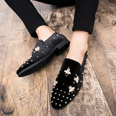 Black corduroy slip-on dress shoes featuring gold bee embellishments and small metal studs.