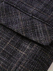 A close-up view of a dark grey blazer featuring a subtle plaid pattern and a notched lapel.