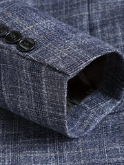 A close-up of a blue textured blazer sleeve featuring a plaid pattern and three black buttons.