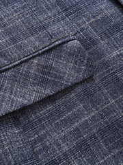A close-up view of a navy blue blazer featuring a subtle white and tan plaid pattern.