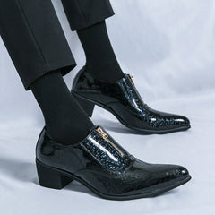 A pair of black patent leather men's dress shoes with a front zipper and a block heel.