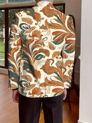 A man wears a single-breasted blazer with an all-over orange and teal floral print.