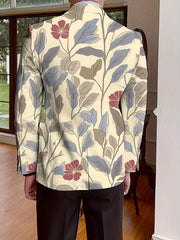 A man wears a cream-colored, single-breasted blazer featuring an all-over floral and leaf print.