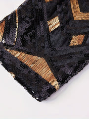 A close-up of a black suit jacket sleeve featuring a geometric pattern of gold sequins.