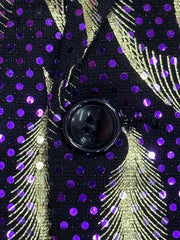 A close-up of a black blazer featuring a purple and gold paisley pattern with a single button.