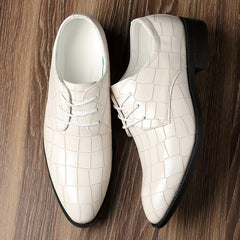 A pair of glossy off-white crocodile-pattern lace-up dress shoes with black rubber soles.