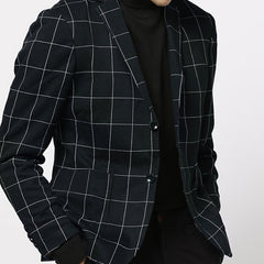 A man wears a black long-sleeve blazer featuring a white grid pattern and a lapel collar.