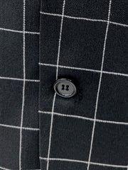 Close-up of a black blazer featuring a white grid pattern and a single black button.