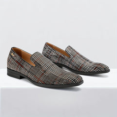 A pair of men's slip-on loafers featuring a black and white plaid pattern with a round toe.