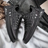 A pair of black low-top sneakers with crocodile-textured uppers and lace-up closures.