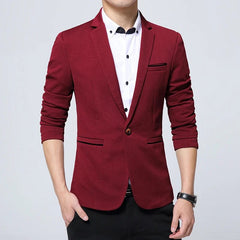 A man wears a slim-fit, single-breasted burgundy blazer with a notched collar over a white shirt.