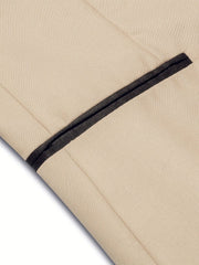 A close-up of a beige blazer featuring a contrasting black pocket detail.