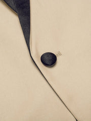 A close-up of a beige blazer featuring a black satin shawl lapel and a single matching button.