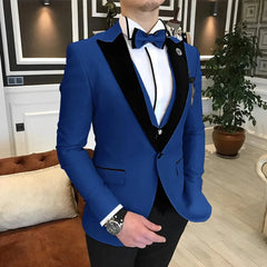 A man wears a royal blue three-piece tuxedo with black velvet lapels, a white shirt, and a bow tie.