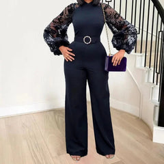 A woman wears a black wide-leg jumpsuit with sheer lace long sleeves and a belted waist.