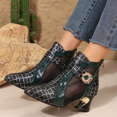 A pair of black mesh pointed-toe ankle boots with a green crocodile-textured strap and gold heel.