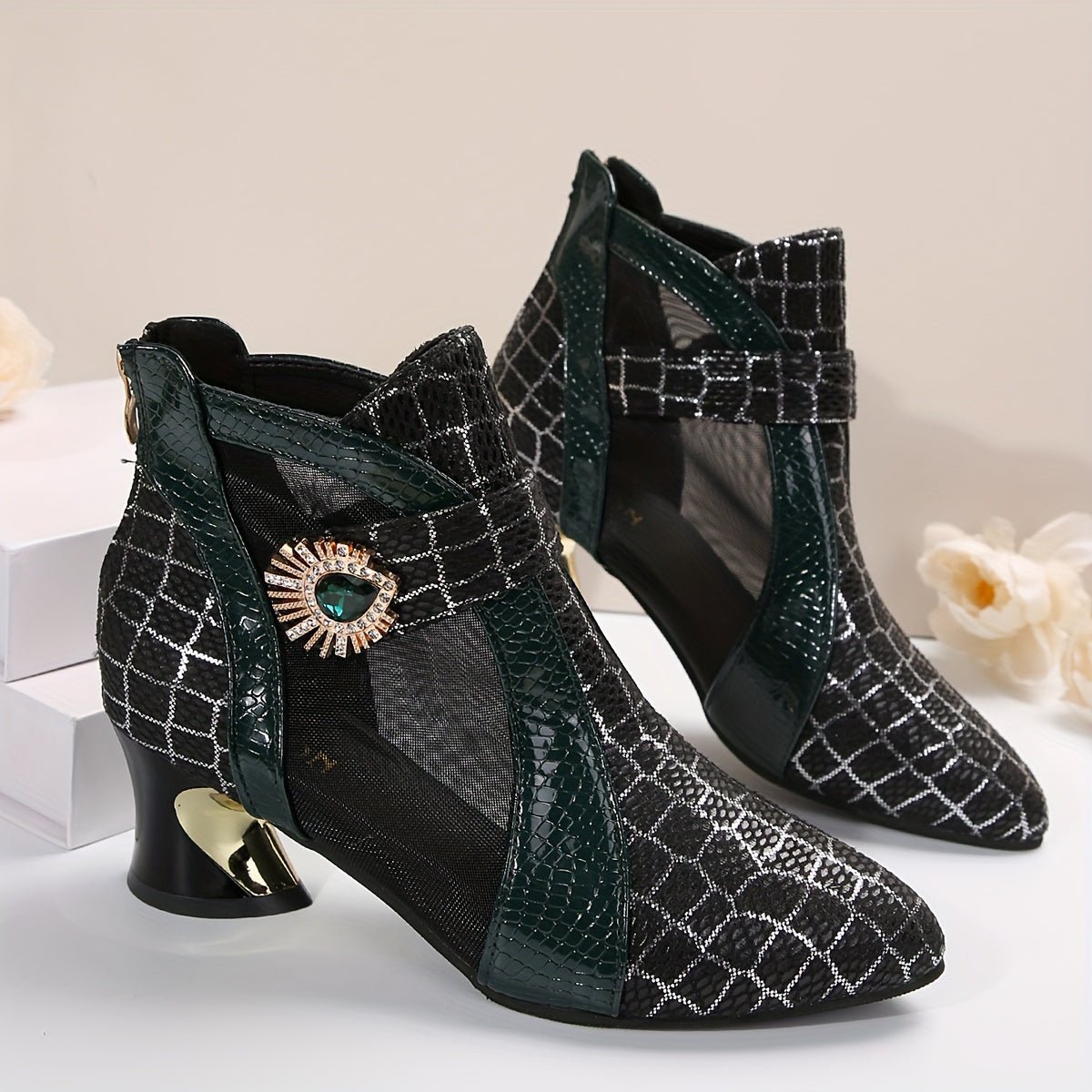 A pair of black mesh ankle boots featuring a pointed toe, block heel, and decorative jewel accent.