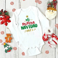 A white long-sleeved baby bodysuit with the text Mi Primera Navidad 2023 printed on the front.